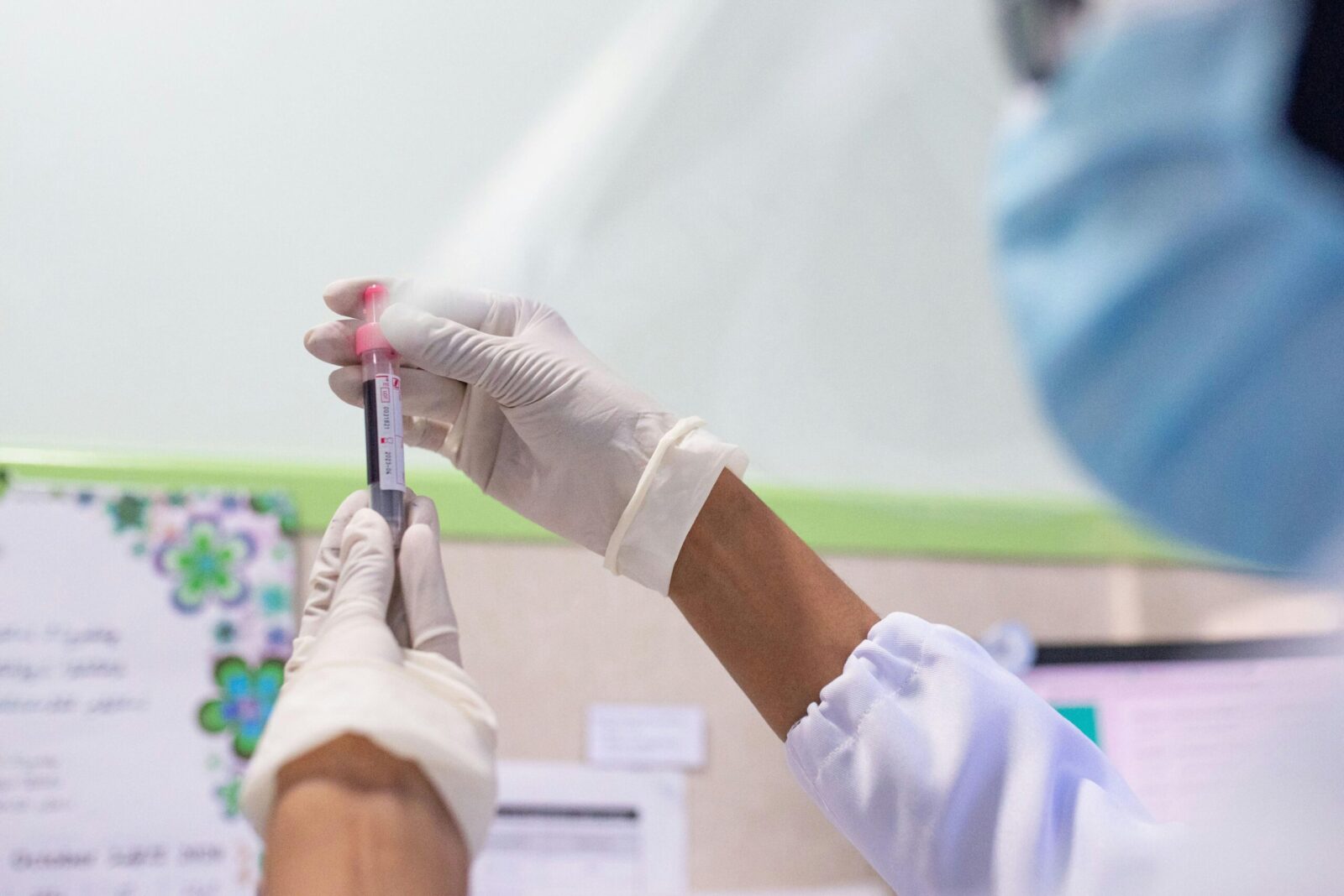 Healthcare worker examining blood sample in laboratory setting for medical analysis.