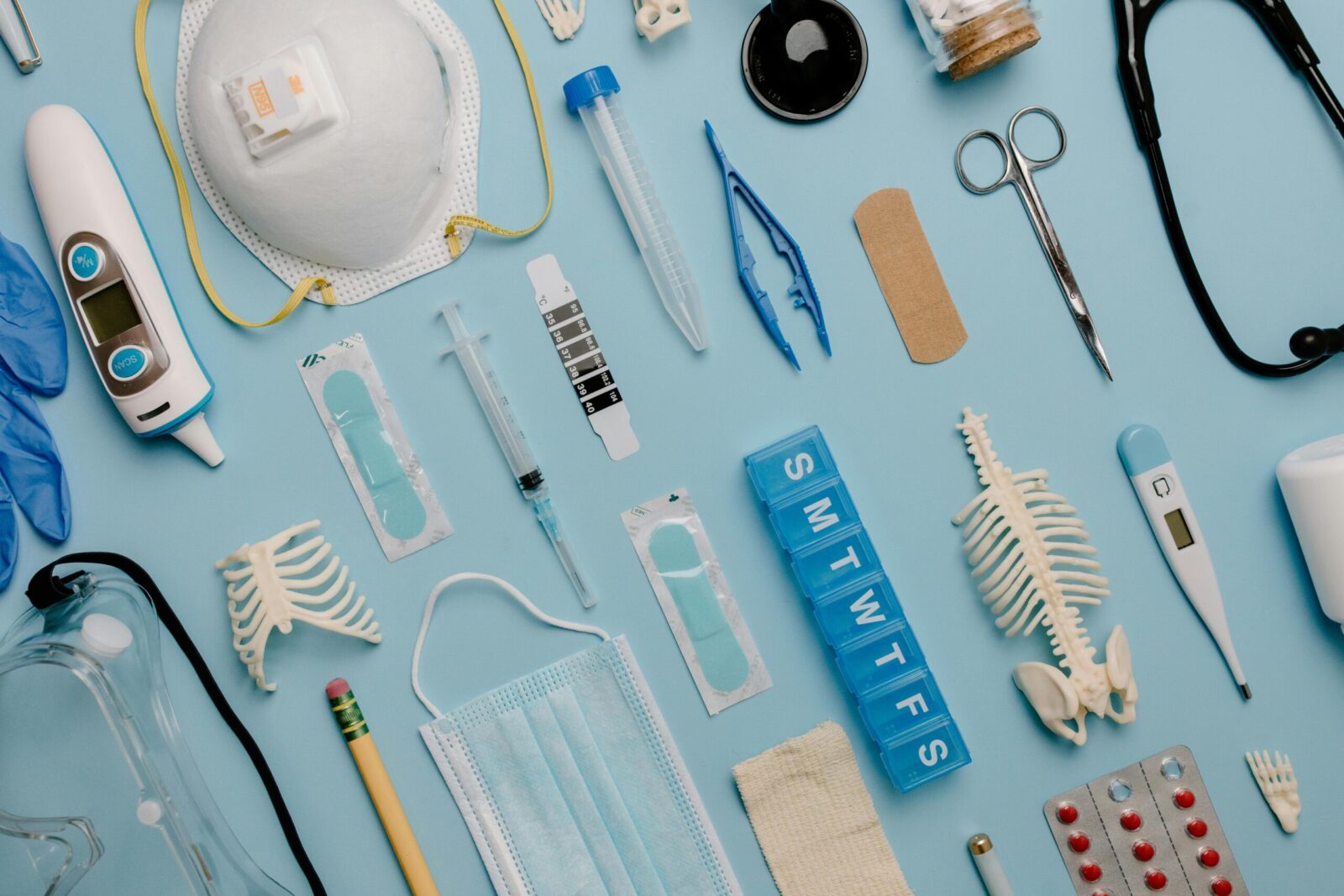 A comprehensive flat lay of diverse medical supplies including PPE and diagnostic equipment on a blue surface.